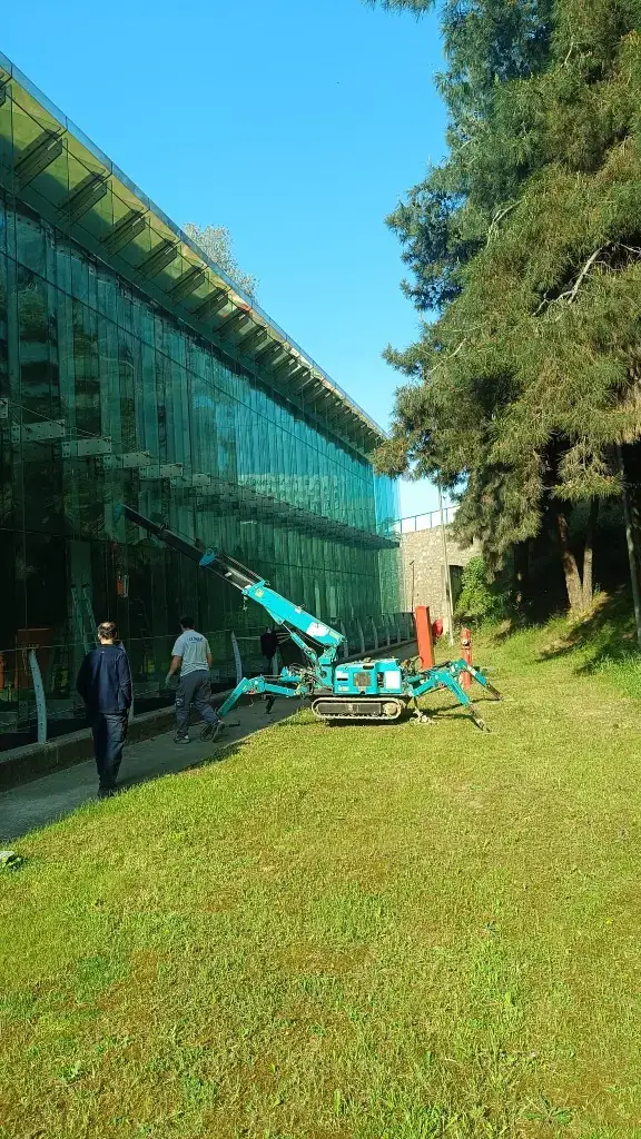 Giydirme cam cephe önünde paletli mini vinçle panel montajı