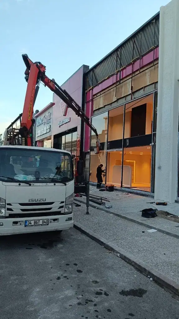 Mağaza cephesi önünde konumlanmış vinçli montaj aracı ve cam vitrin açıklıkları