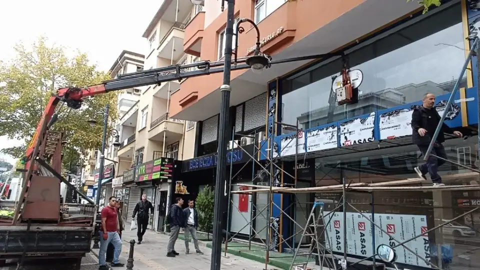 Cadde üzerindeki bir mağaza vitrinine vinç yardımıyla büyük cam panelin yerleştirilmesi